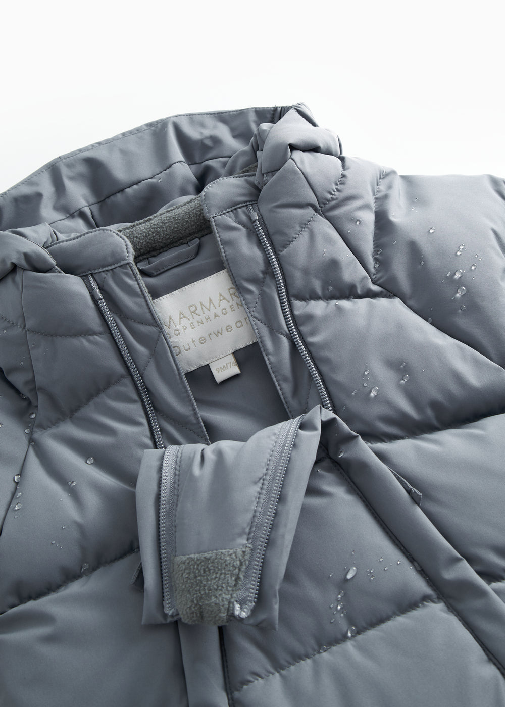 Dark gray jumpsuit with front zipper, sewn-in label, and small water droplets on the padding.