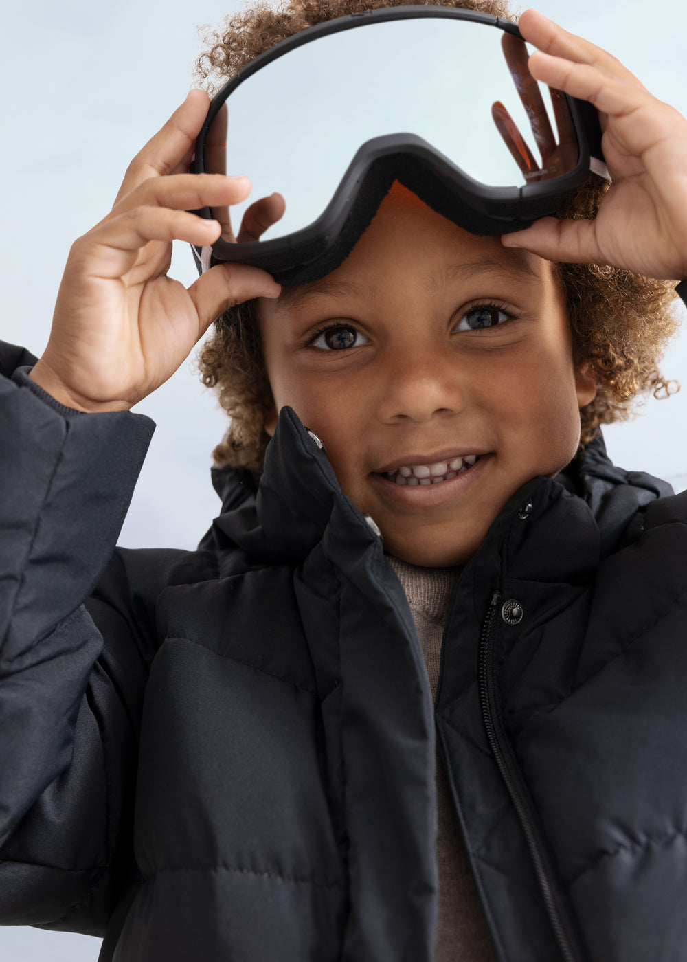 Children's down jacket in model with hood and padded lining.