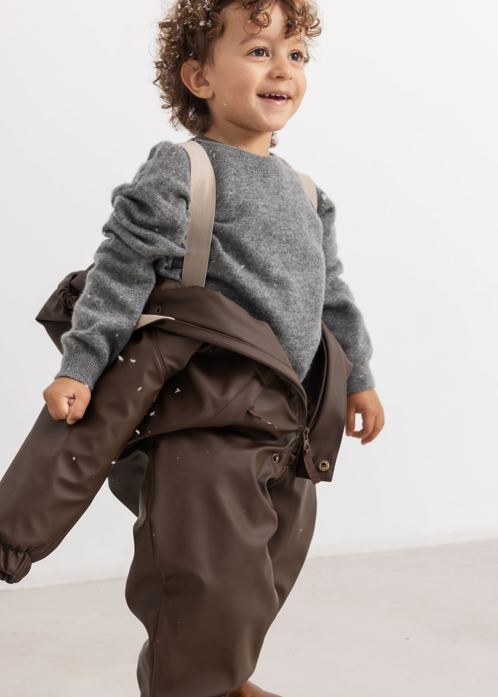 The PU jacket in dark brown with hood and large pockets, seen from the side.