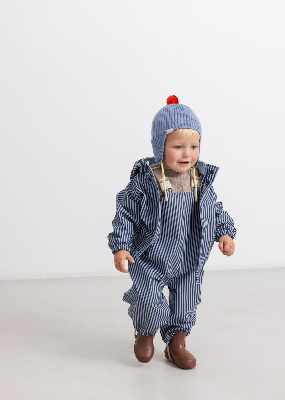 Kids raincoat in blue stripes with hood and zipper, matching trousers.