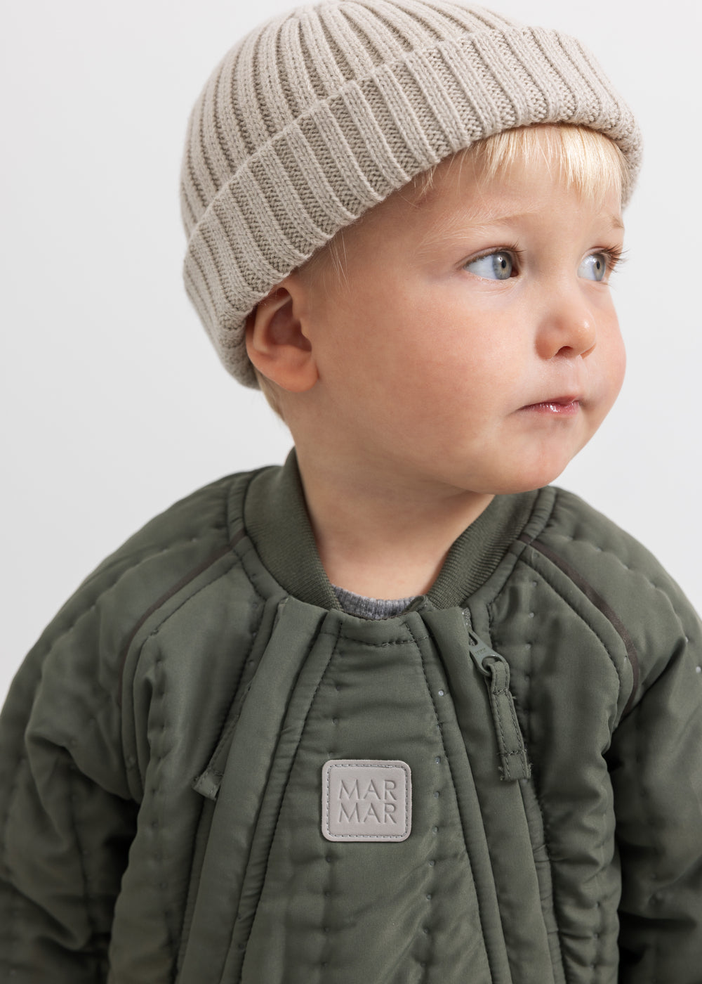 Jacket with zipper and MAR label, dark olive, with beige knit cap.