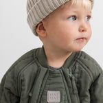 Jacket with zipper and MAR label, dark olive, with beige knit cap.