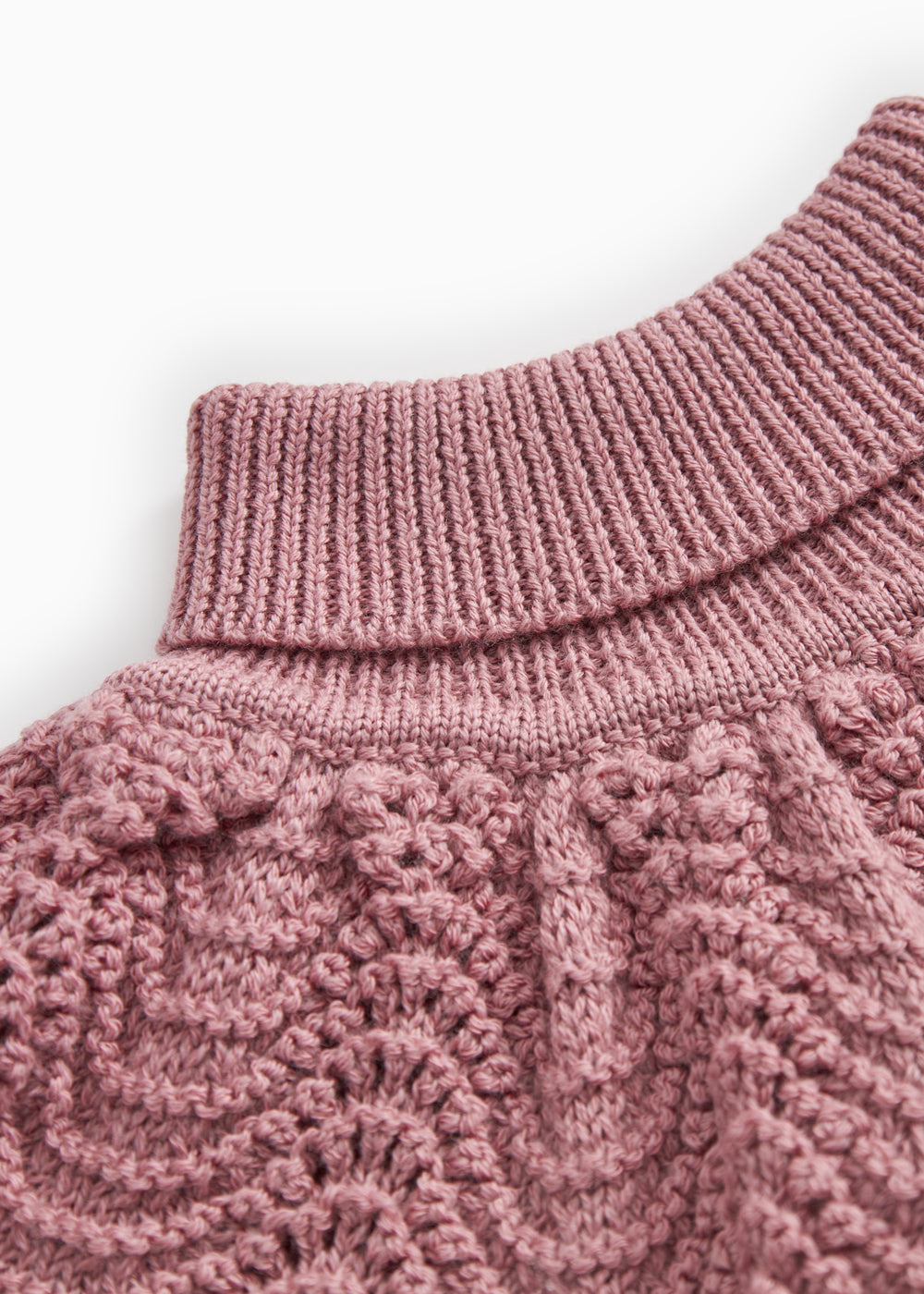 Knitted turtleneck with high rib collar and twisted pattern in muted rose color.