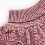 Knitted turtleneck with high rib collar and twisted pattern in muted rose color.