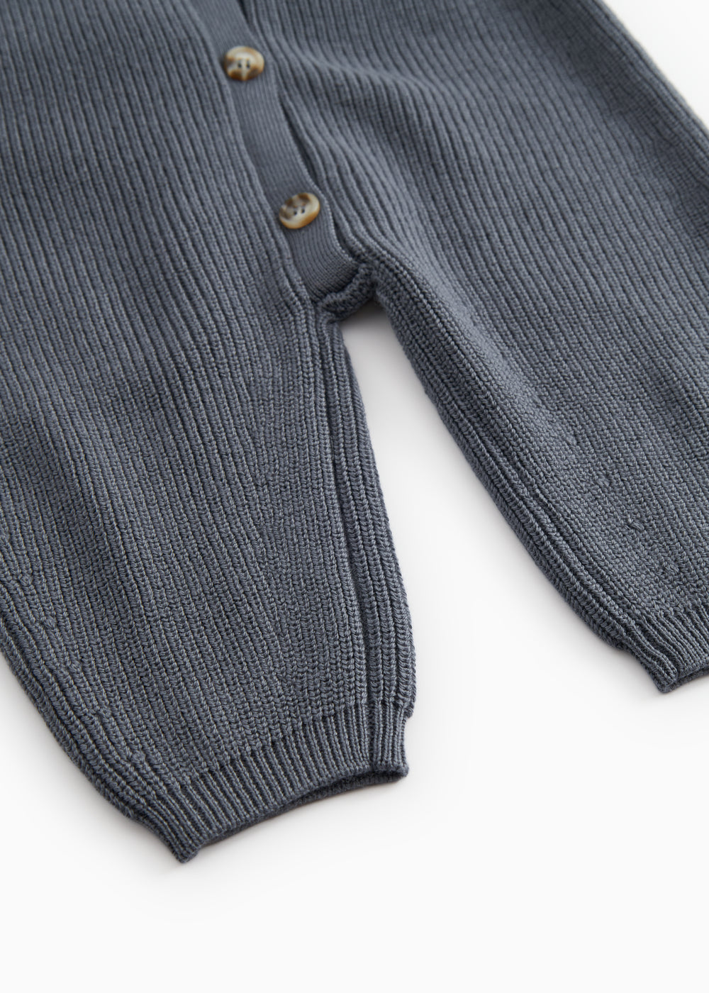 Dark blue knit suit with button closure and ribbing at the sleeves and legs.