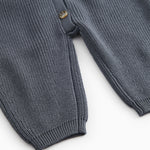 Dark blue knit suit with button closure and ribbing at the sleeves and legs.