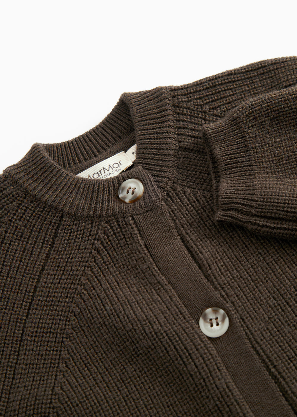 Close-up of a dark knit sweater collar with buttons and a label at the neck.