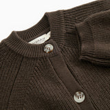 Close-up of a dark knit sweater collar with buttons and a label at the neck.