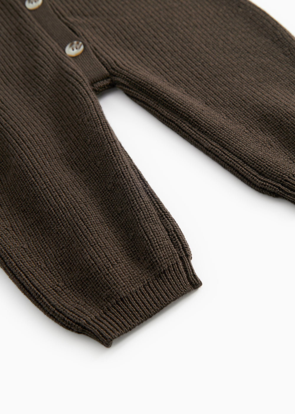 Dark sweater suit with ribbed edges and button closure, visible buttons at the sleeve edge.
