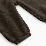 Dark sweater suit with ribbed edges and button closure, visible buttons at the sleeve edge.