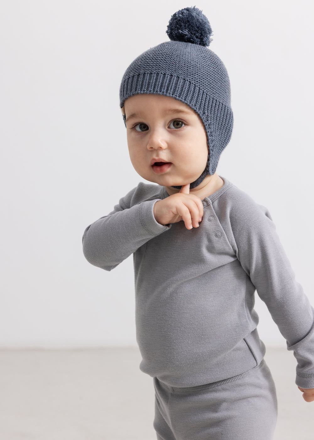 Gray striped hat with pompom, ribbed edge and ear pocket