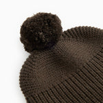 Dark brown knit cap with a large pom-pom and ribbed knit pattern.