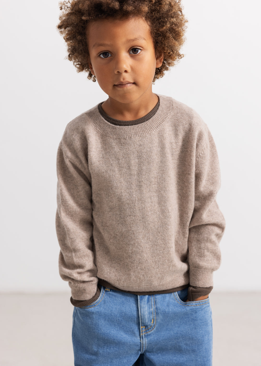 Gray knitted blouse with round collar and ribbed edges, worn with blue jeans.