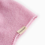 Pink baby hat in knit with a small tag at the edge