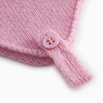 Pink baby hat in knit with button detail and drawstring.