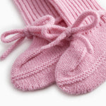 Details of pink knitted baby clothes with a bow front band.