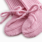 Details of pink knitted baby clothes with a bow front band.