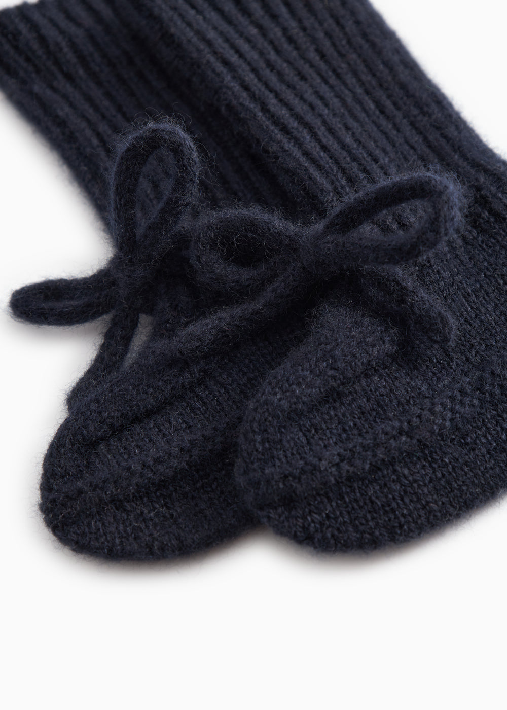 Indigo knitted baby shoes with a bow strap in front and a visible heel.