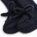 Indigo knitted baby shoes with a bow strap in front and a visible heel.