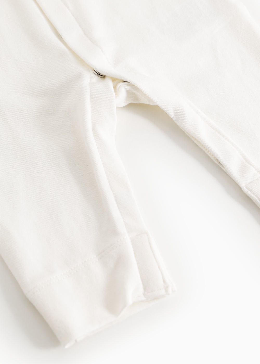Off-white dress with a slit at the leg opening and smooth fabric at the seam.