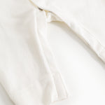 Off-white dress with a slit at the leg opening and smooth fabric at the seam.