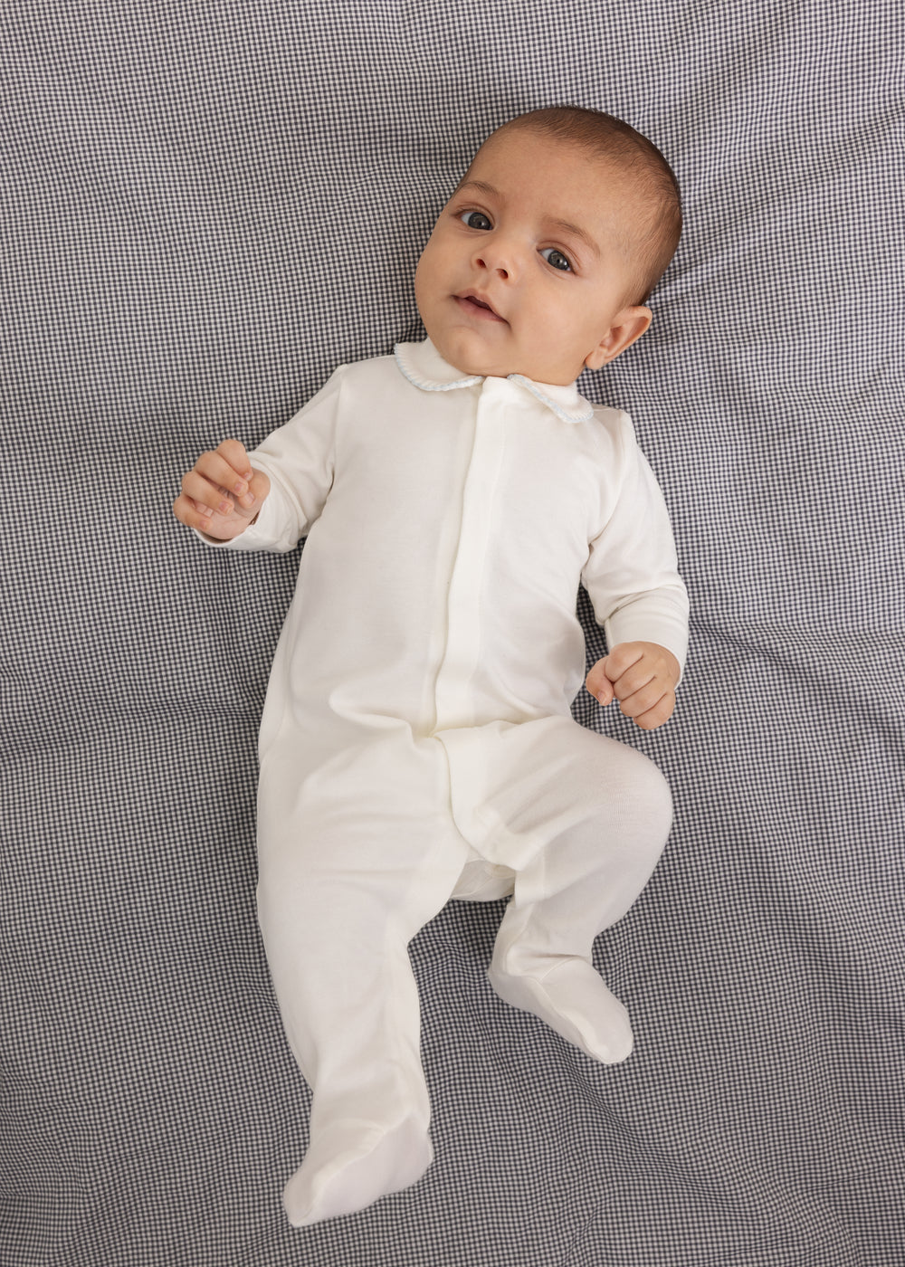 White baby romper with a blue picot collar edge and full-length legs to the feet.