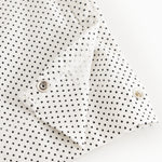 White baby top with small black dots and snap closure at the shoulder