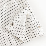 White baby top with small black dots and snap closure at the shoulder