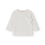 White blouse for baby with small black dots, round collar and front tie.