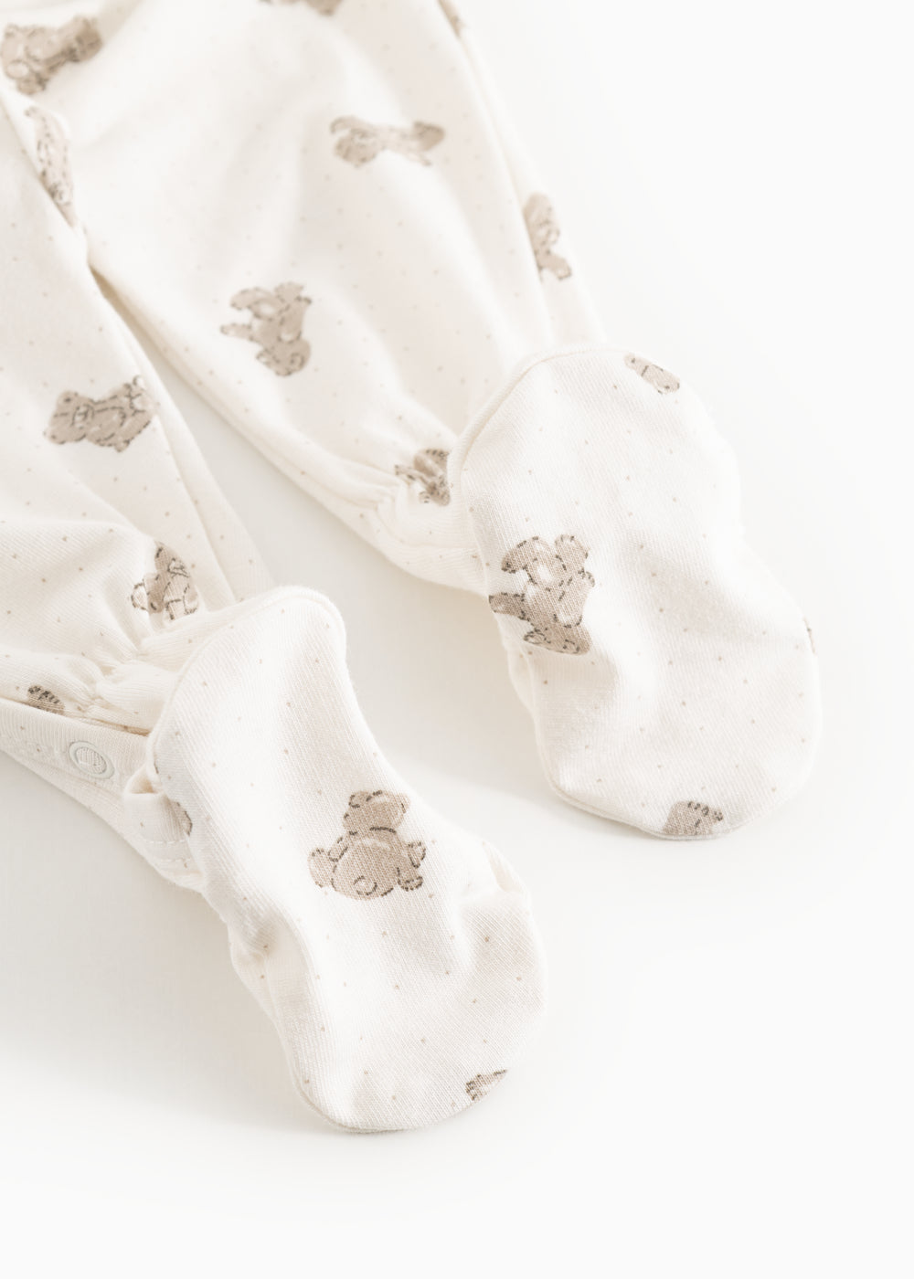 White dress with beige teddy bear print and long legs, shown as a close-up at the feet.