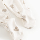 White dress with beige teddy bear print and long legs, shown as a close-up at the feet.