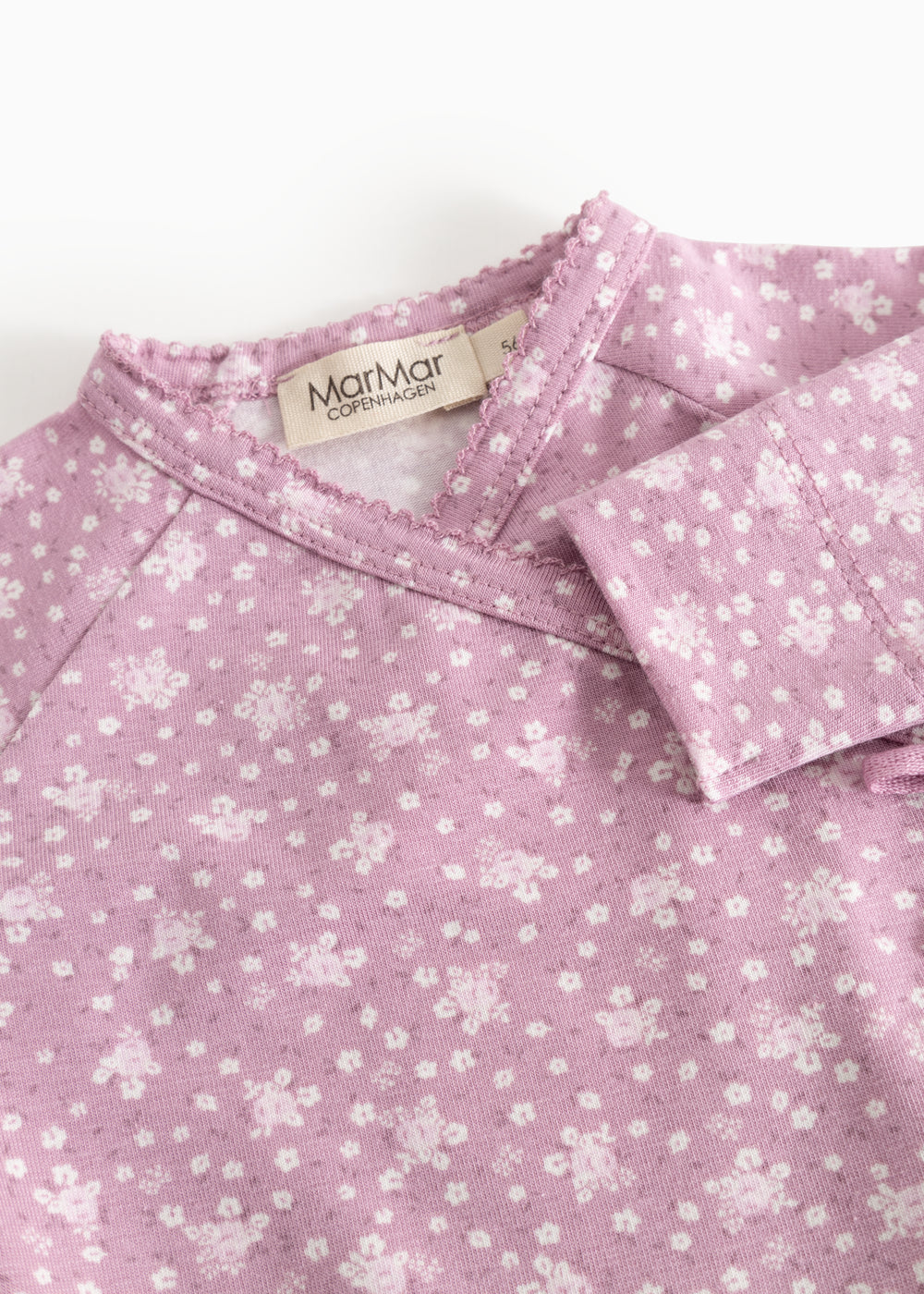 Rubetta dress in pink with small white‑rose floral print and a criss‑cross collar with a label.