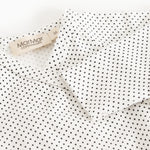 White dress with small black dots, collar with label.