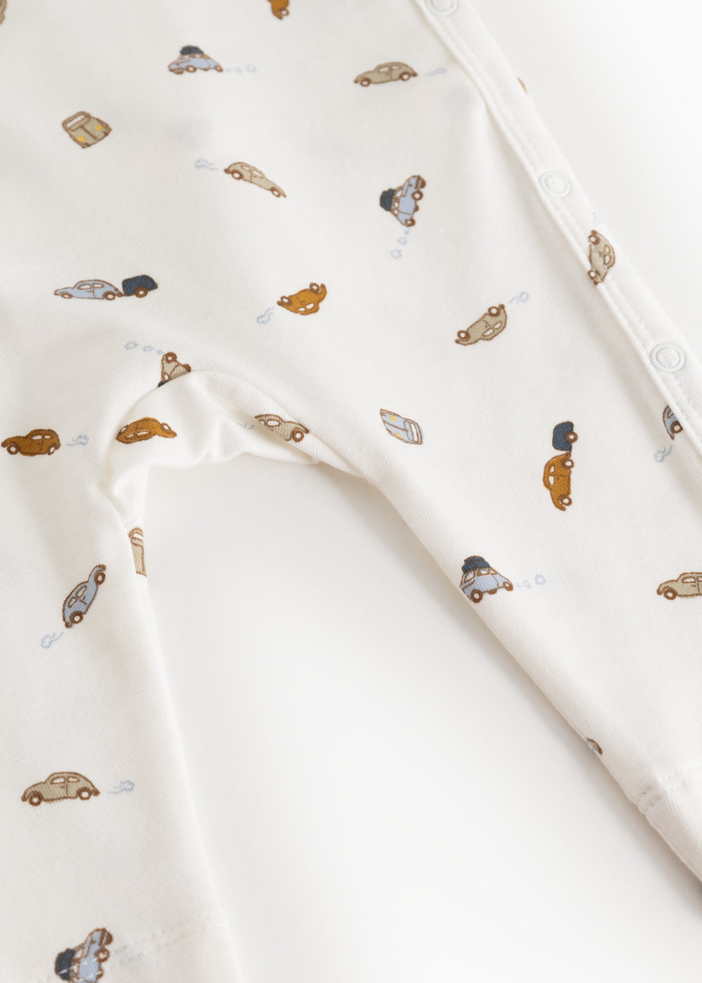 White dress with colored car print and printed button at shoulder.