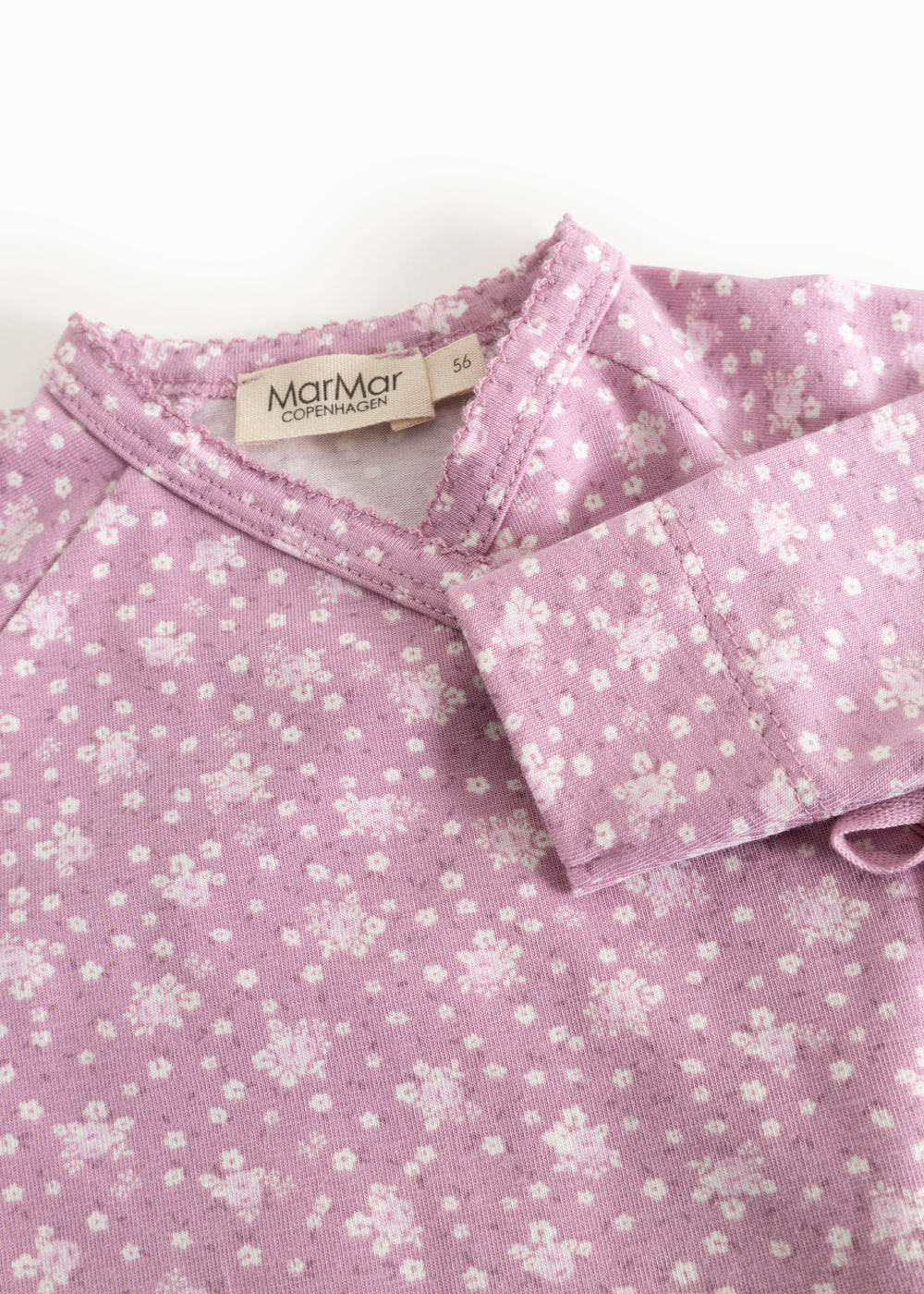 Dress from Rula in pink with white flowers, cross neckline, and buttons.