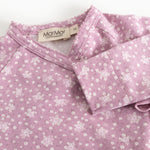 Dress from Rula in pink with white flowers, cross neckline, and buttons.