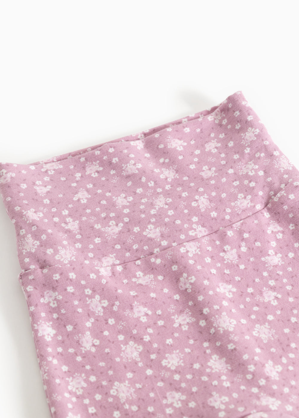 Pink trousers with small white flower print and seam at the waist.