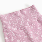 Pink trousers with small white flower print and seam at the waist.