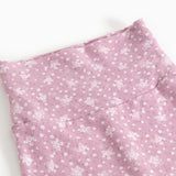 Pink trousers with small white flower print and seam at the waist.