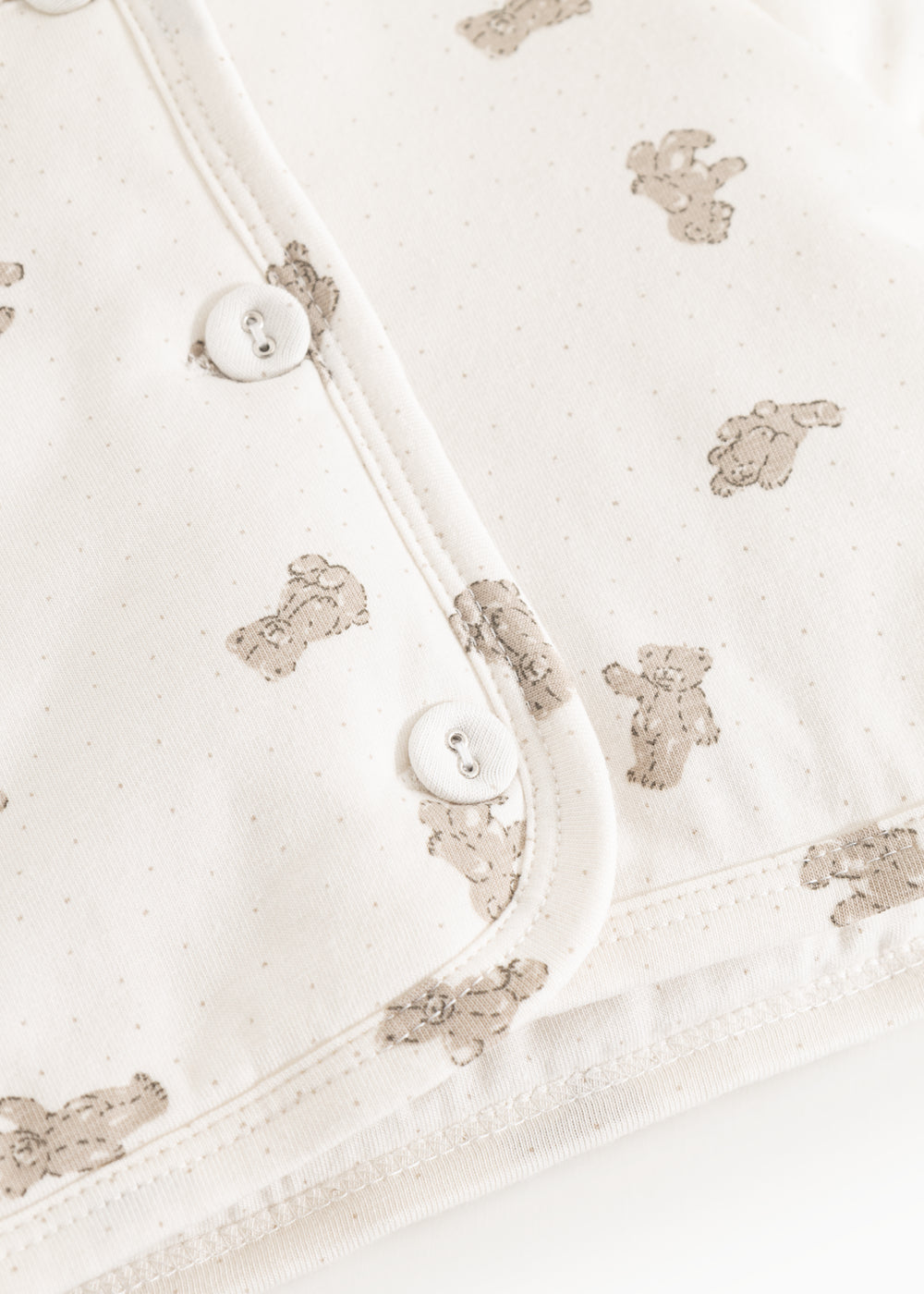 Hooded winter jacket, cream side with teddy bear print and snap buttons.