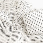 Details of a white jacket with small black dots, hood, and buttons at the front.