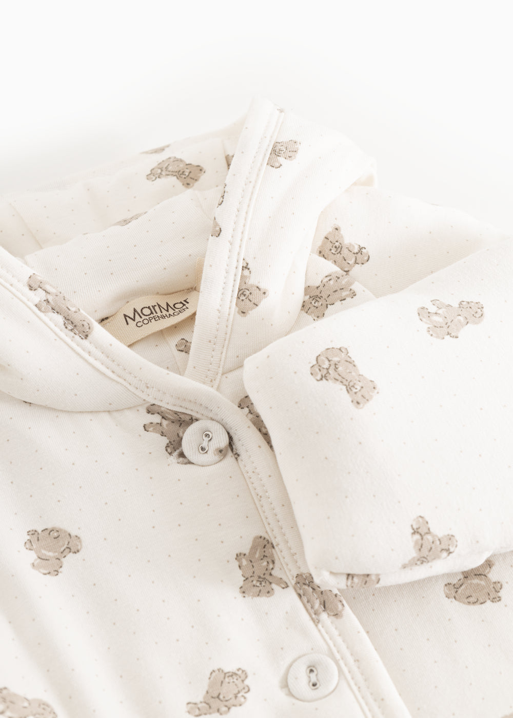 White dress with beige teddy bear print, hood and button closure at the neckline.