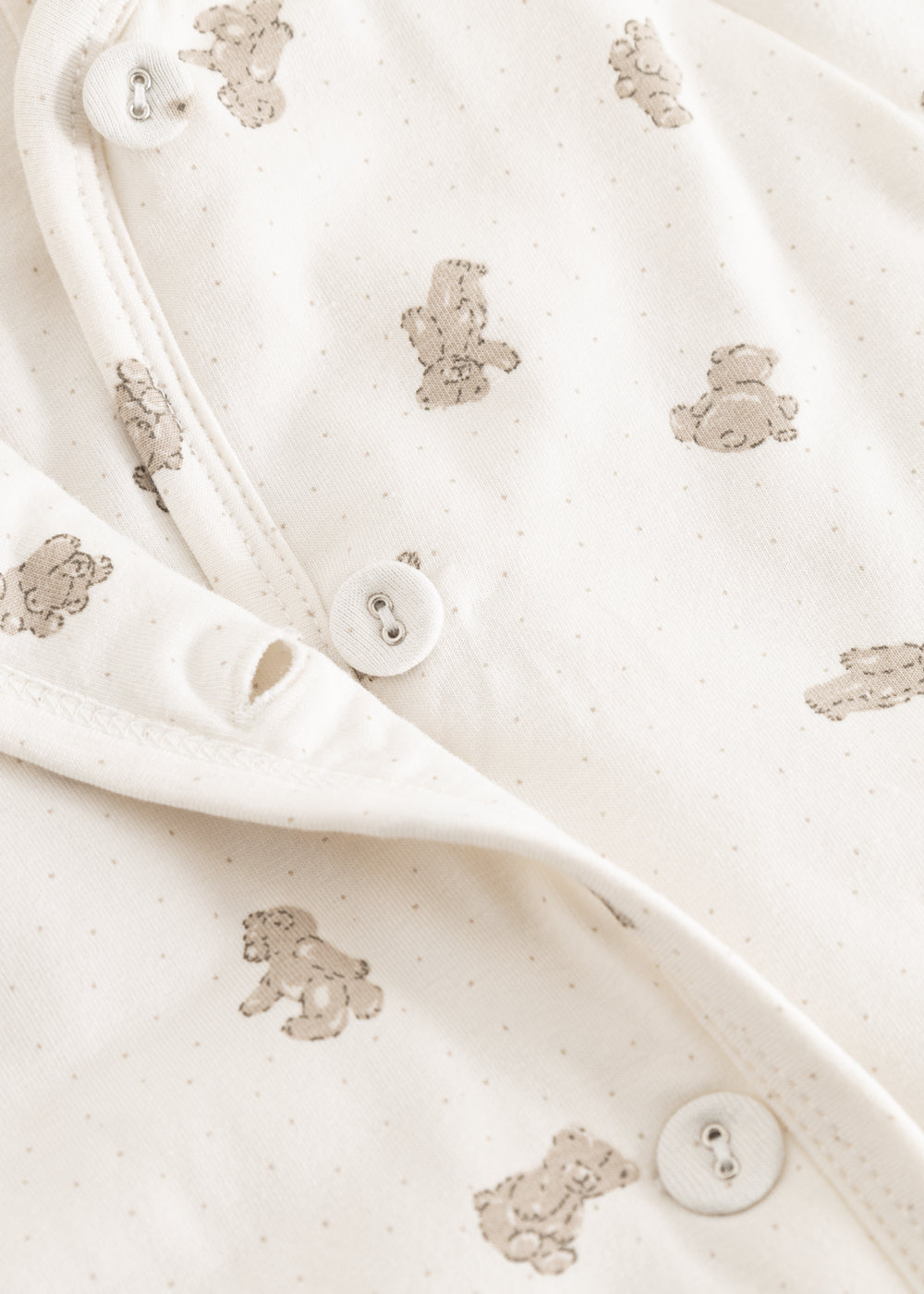 White dress with beige teddy bear pattern and snap buttons at the opening