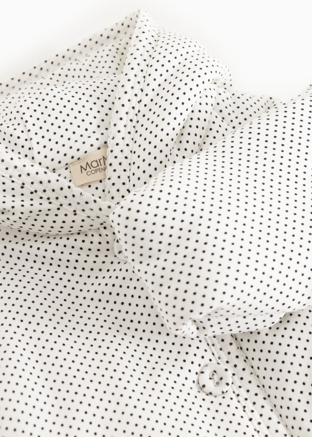 White dress with small black dots, collar and button detail in front.