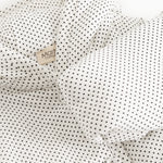 White dress with small black dots, collar and button detail in front.