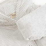 White dress with small black dots, collar and button detail in front.