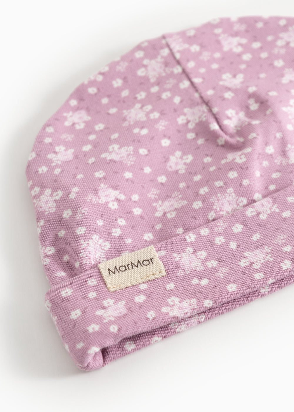 Pink baby onesie/cap with small white flowers and a label on the front.