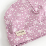 Pink baby onesie/cap with small white flowers and a label on the front.
