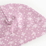 Pink baby onesie cap/hat with small white flowers and a sweet detail at the top