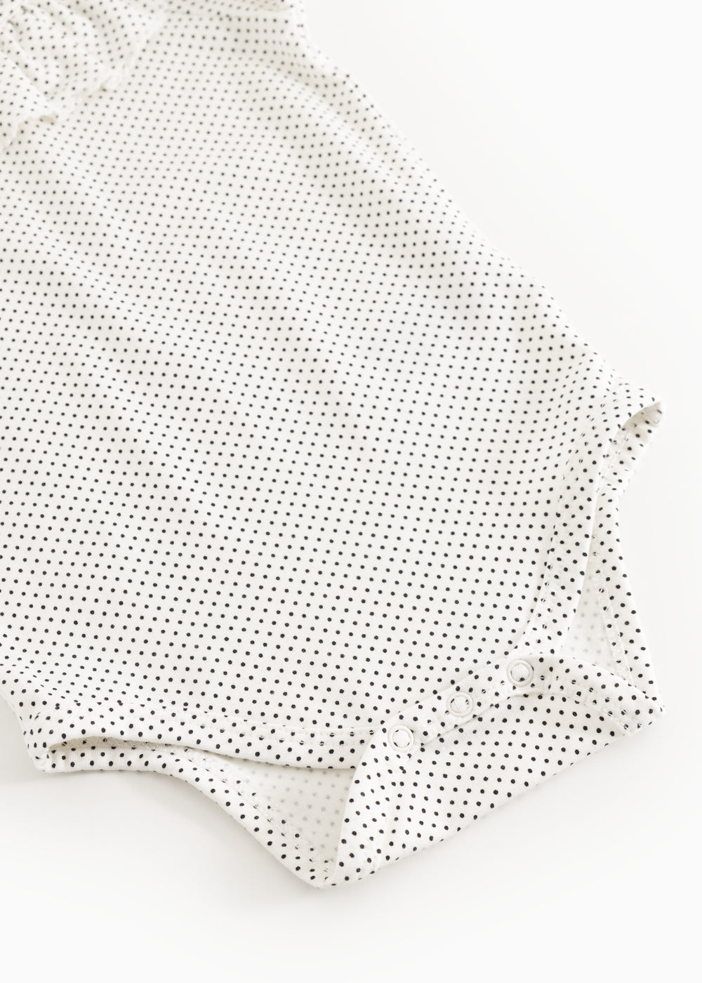 Baby bodystocking with small black dots, long sleeves and buttons at the legs.